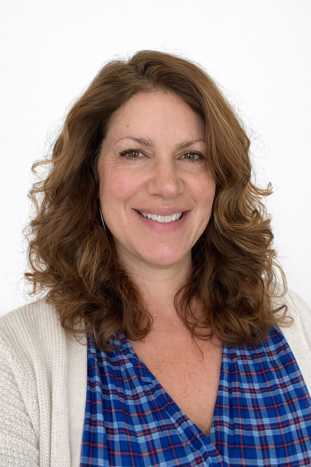 Smiling woman with curly hair in a casual outfit.