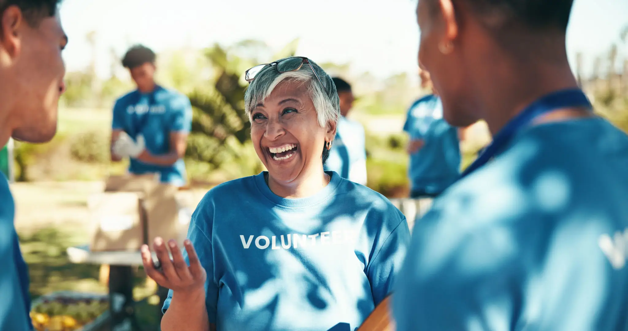 A joyful volunteer woman laughing during an outdoor event.