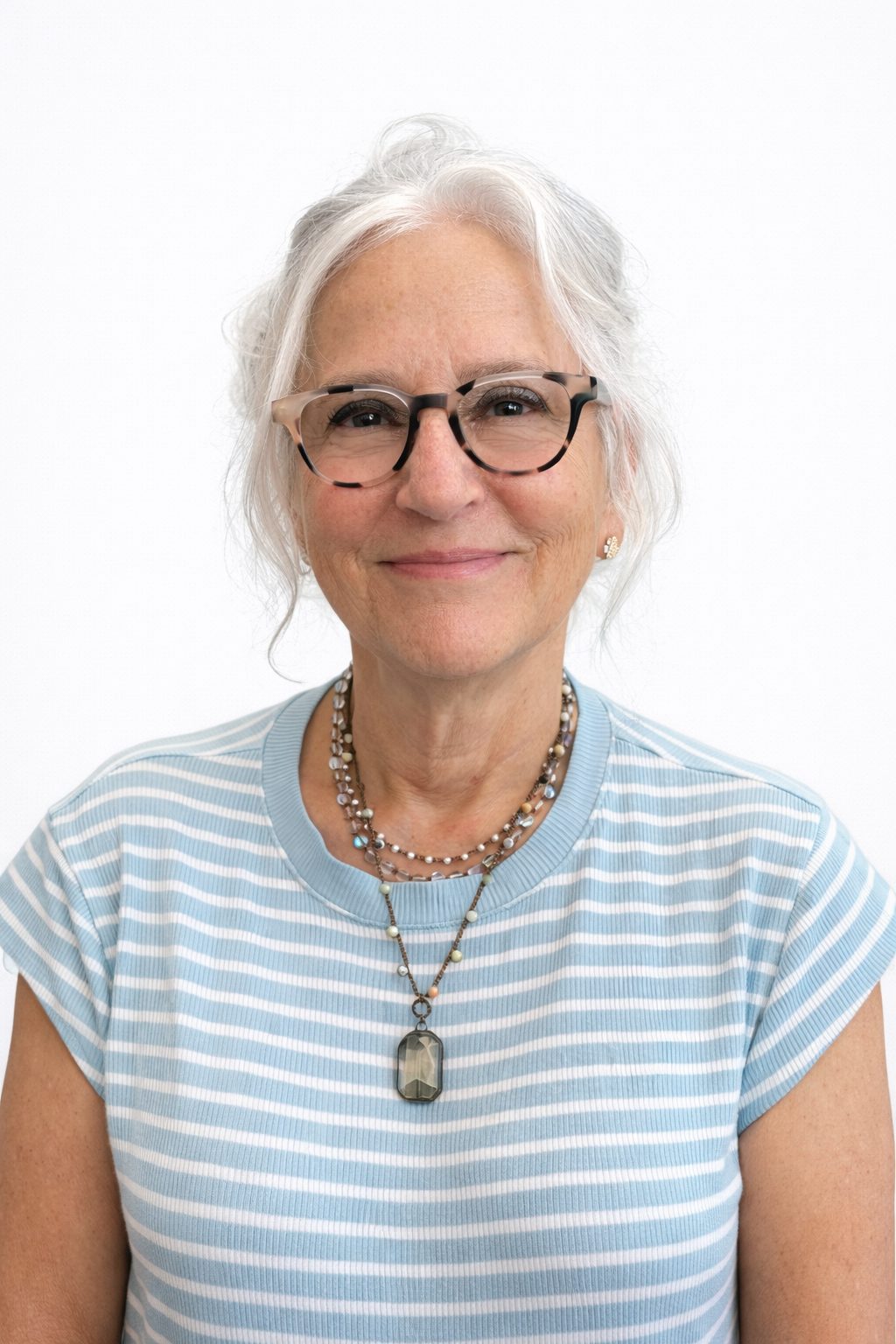 Smiling elderly woman with glasses and a striped shirt.