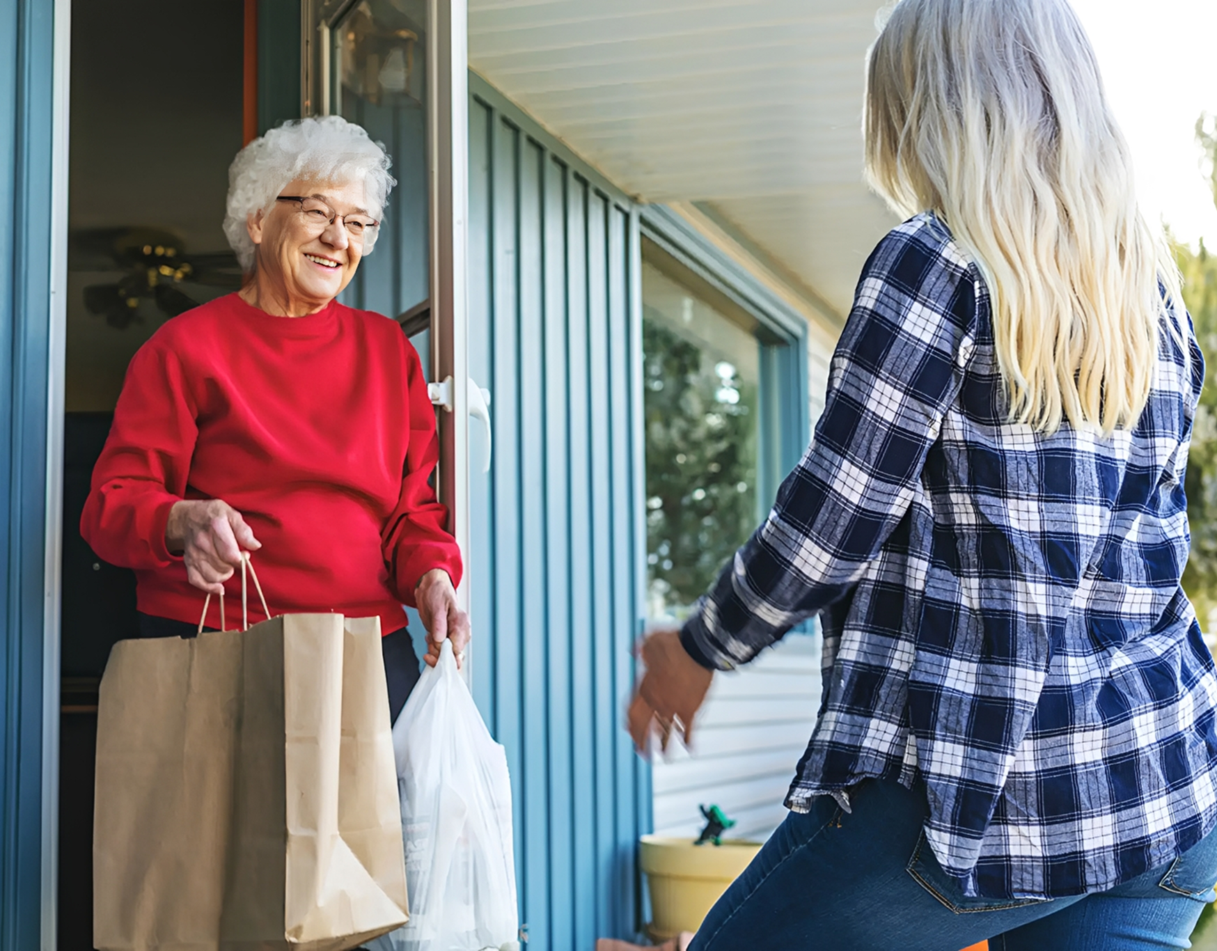 an elderly person being delivered a bag of food at their door