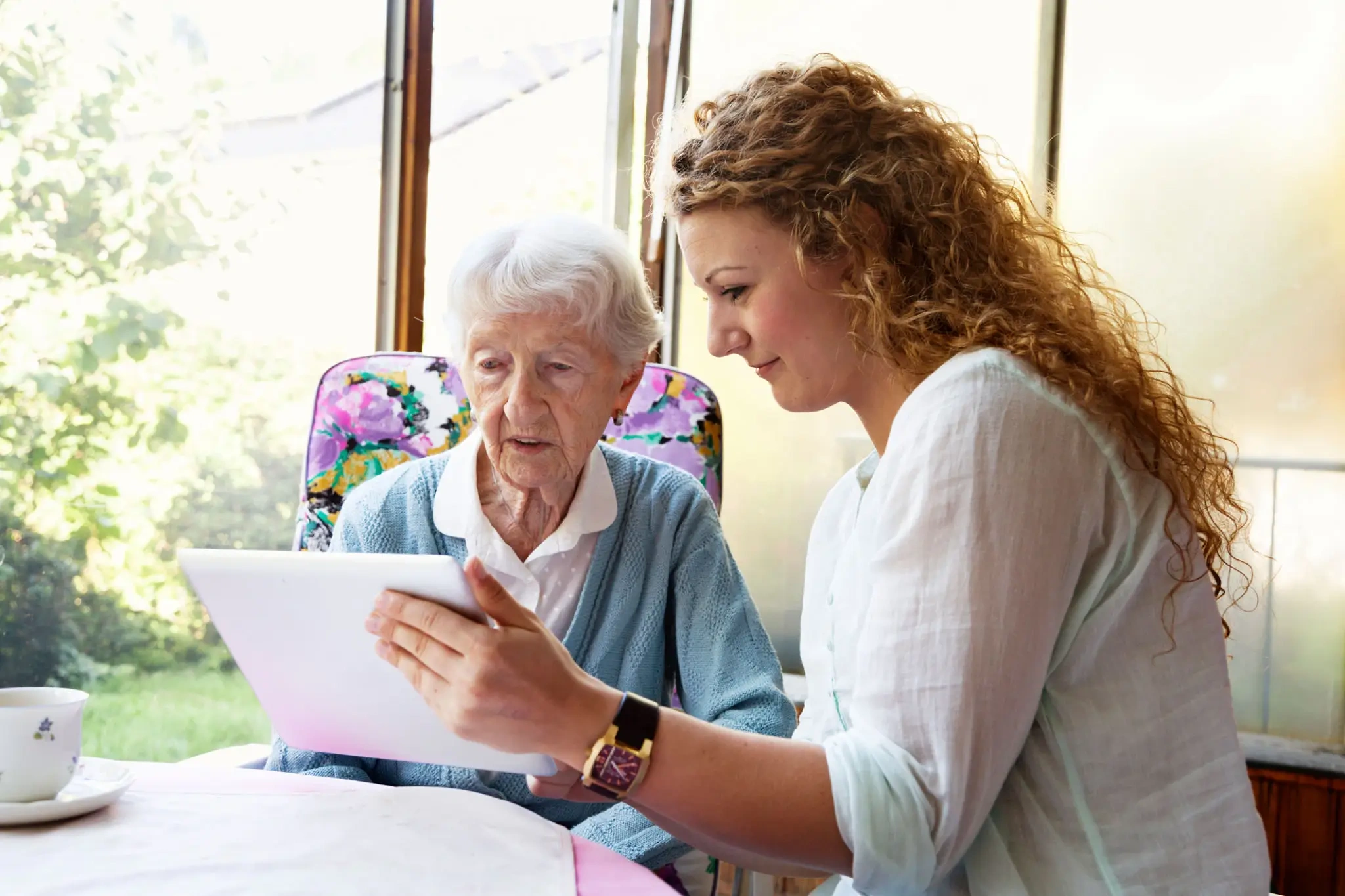 Young woman helping elderly woman with paperwork.