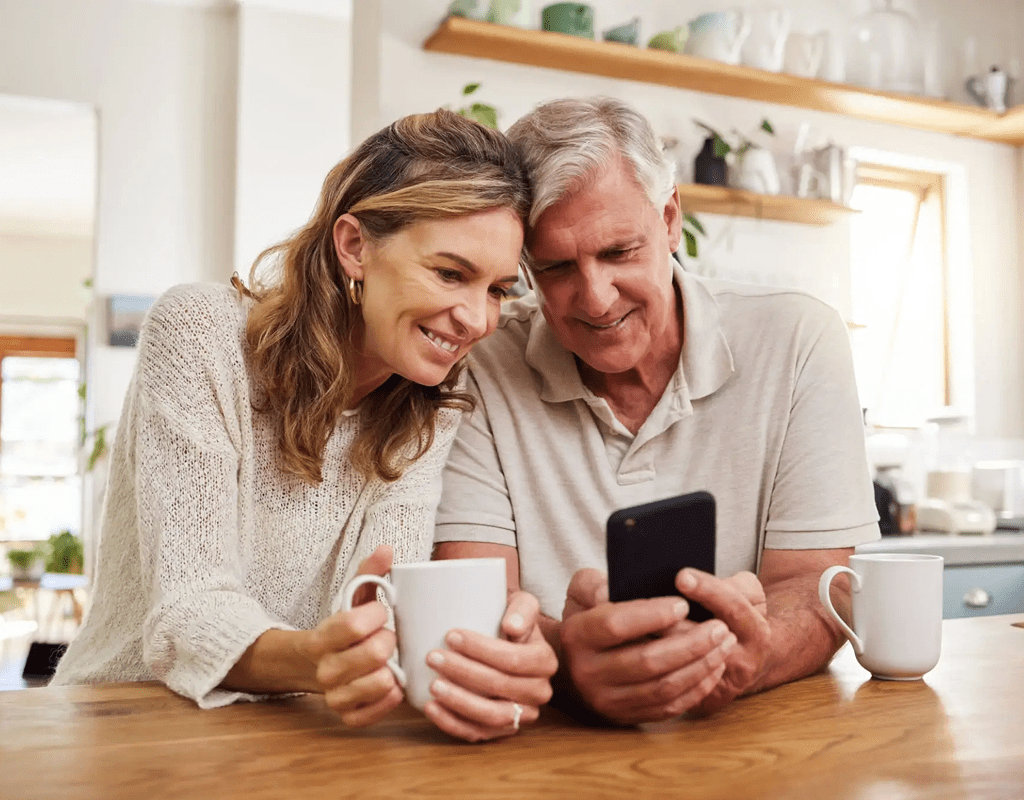 A smiling couple sharing a moment while looking at a phone.