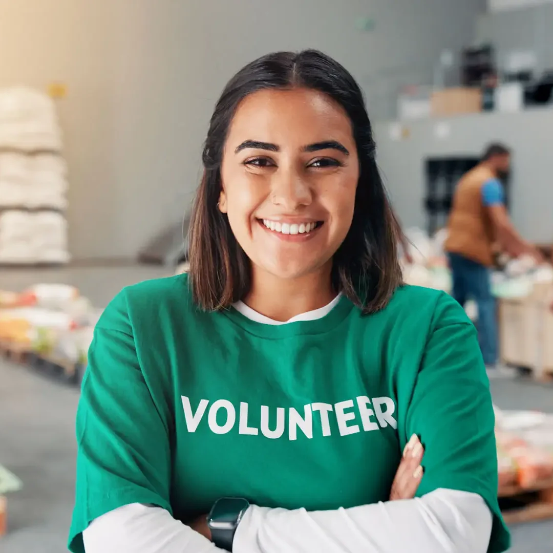 Smiling volunteer in a green shirt with arms crossed.